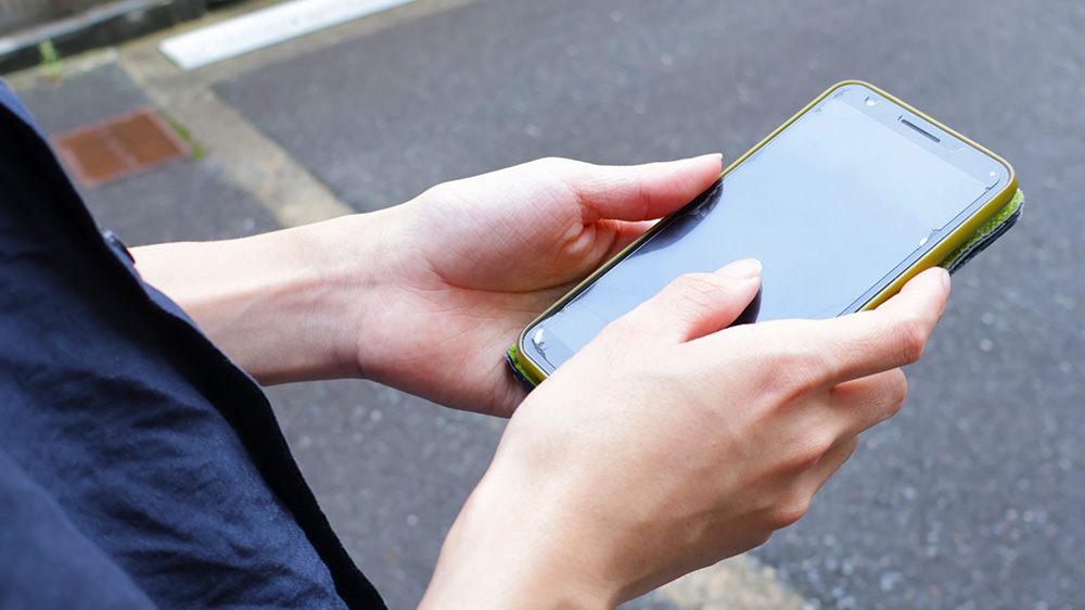 外でスマホを触る手元の写真