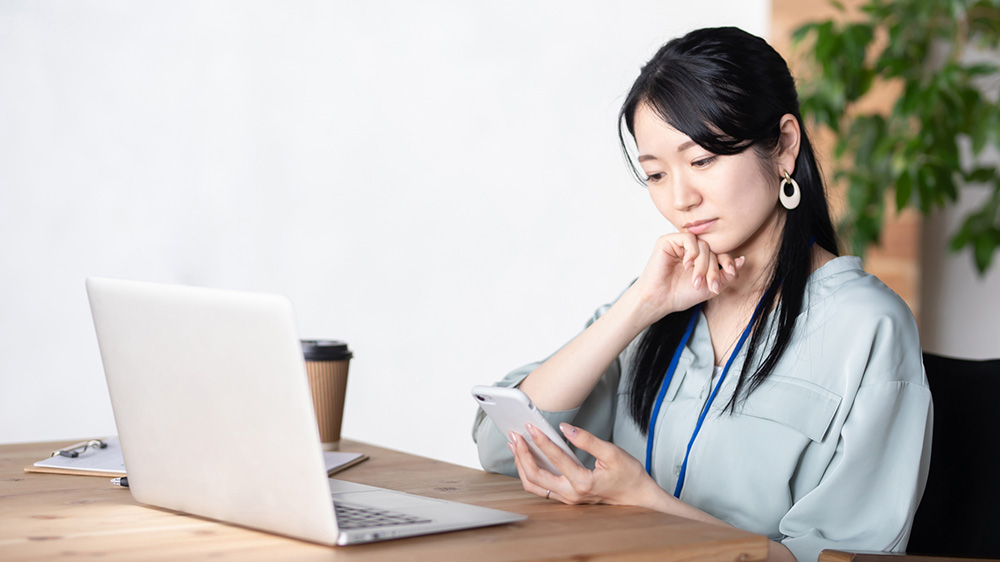 スマホとPCをみて考える女性